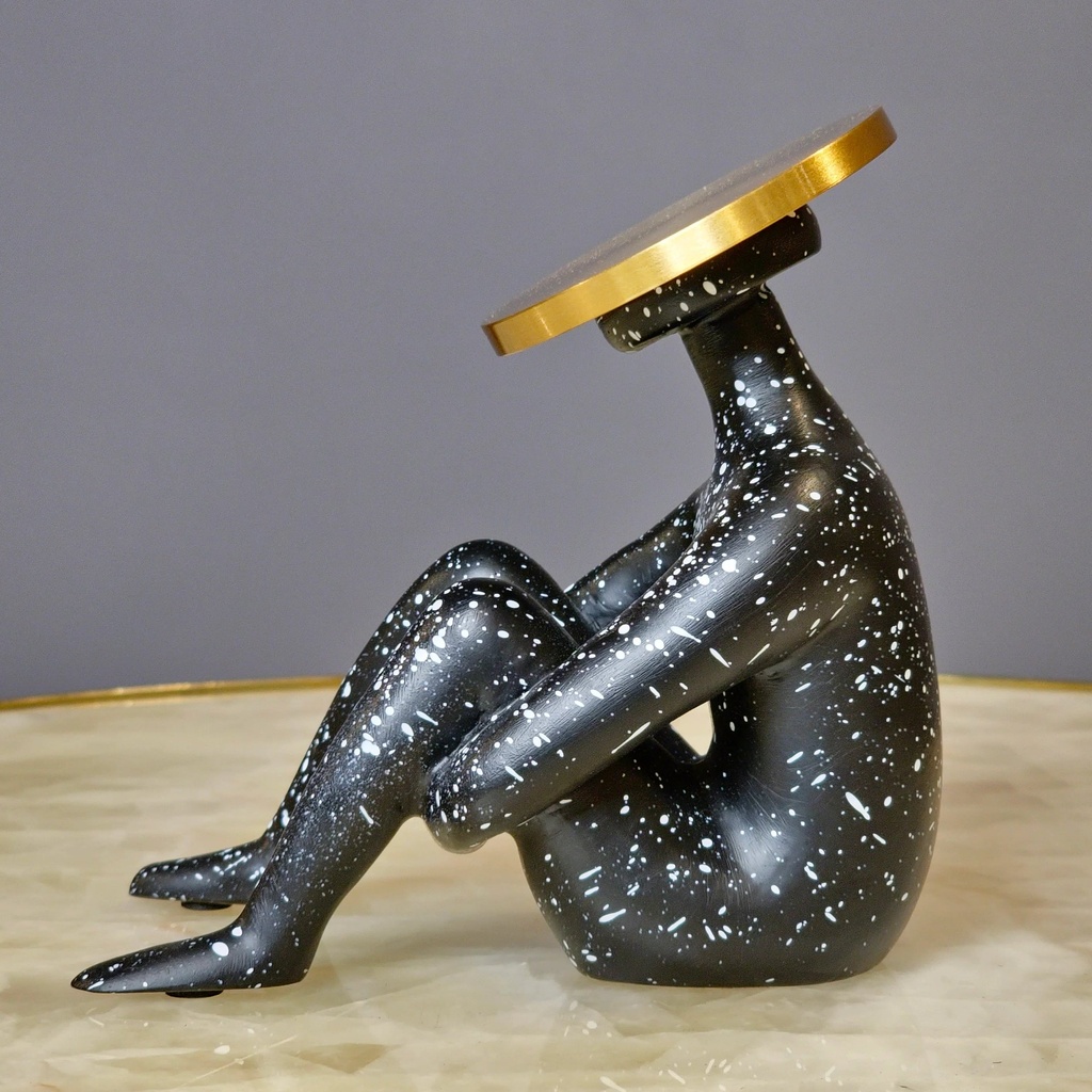 Black ceramic table lamp on a console table below a large wood wall sculpture in an organic modern room