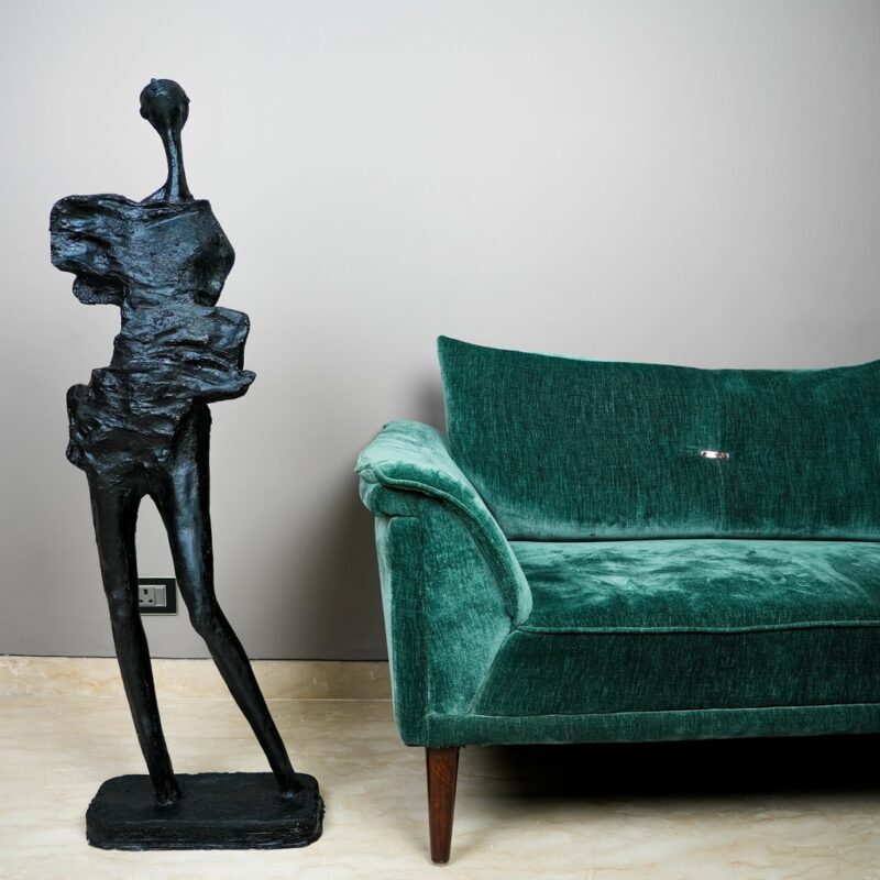 Metal wall sculpture — gold petal lamp on a console table below a large brass relief wall panel