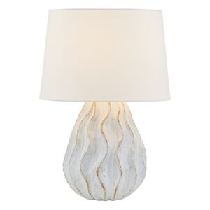 Pale blue ceramic table lamp beside a rattan chair in a bohemian living room with warm wood and linen