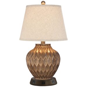 Bird sculpture — bronze accent table lamp on a covered patio table with a bronze garden bird sculpture beside a garden pond