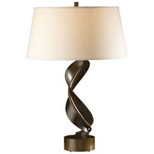 Mercury glass table lamp on a dark wood console — the silvered surface amplifying warm LED light in a moody room
