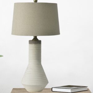 Mauve ceramic lamp with brass hardware in a warm bohemian bedroom with linen textiles and woven accessories