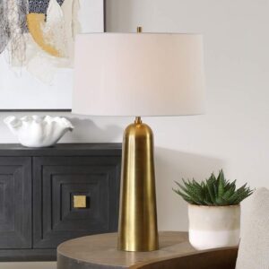 Cobalt blue glass table lamp with brass base beside dark green velvet throw in a moody living room