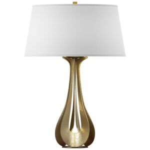 Brass table lamp styled on a bedroom nightstand with a stack of books and a small potted plant