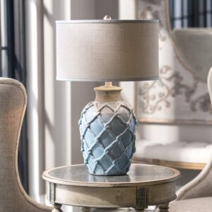 Sculptural table lamp — pale blue ceramic sculptural lamp on a bedroom nightstand beside a horizontal headboard composition