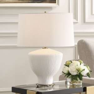 Green ceramic table lamp with white shade on a wooden console in a warm transitional living room