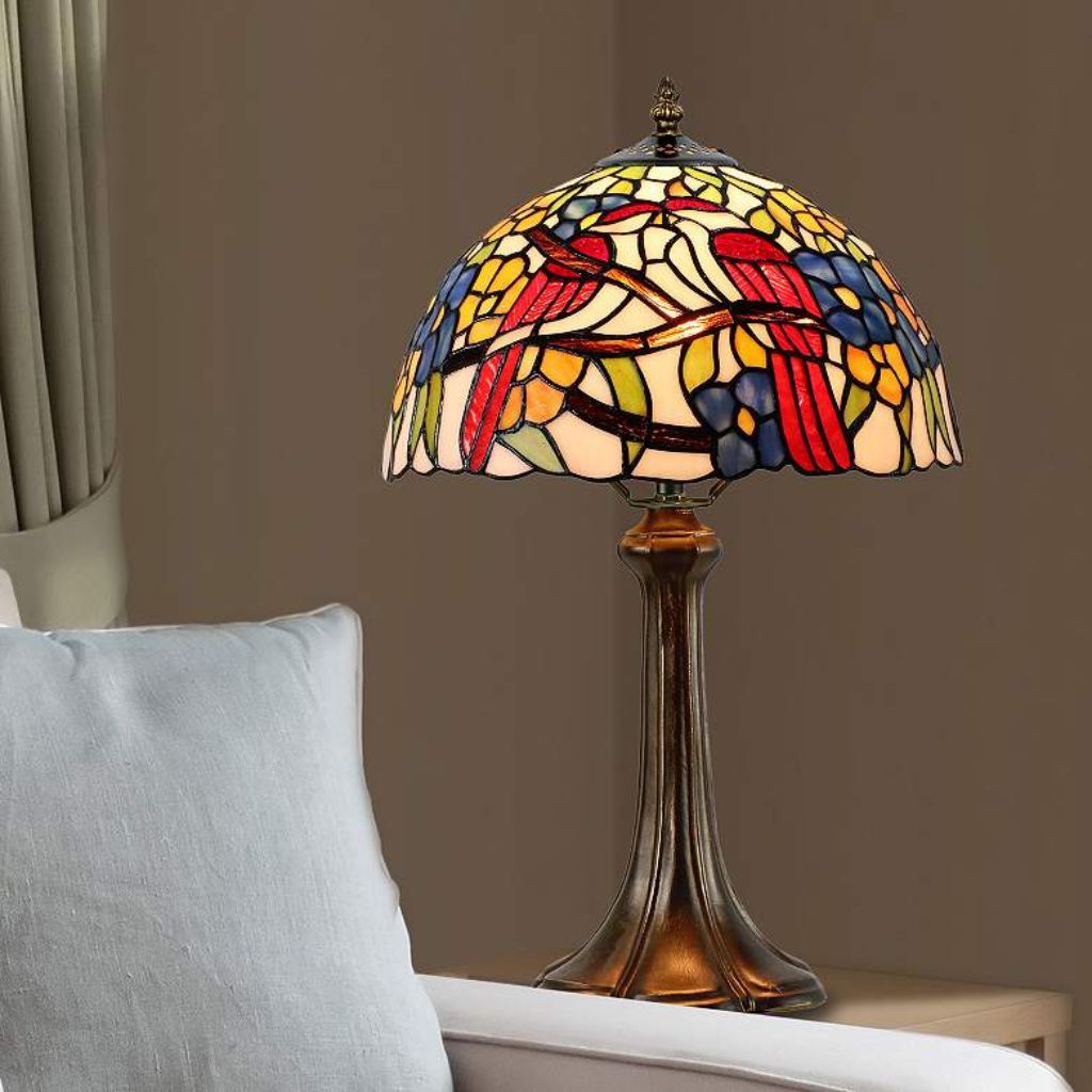 Tiffany style table lamp casting coloured stained glass light across an art deco study