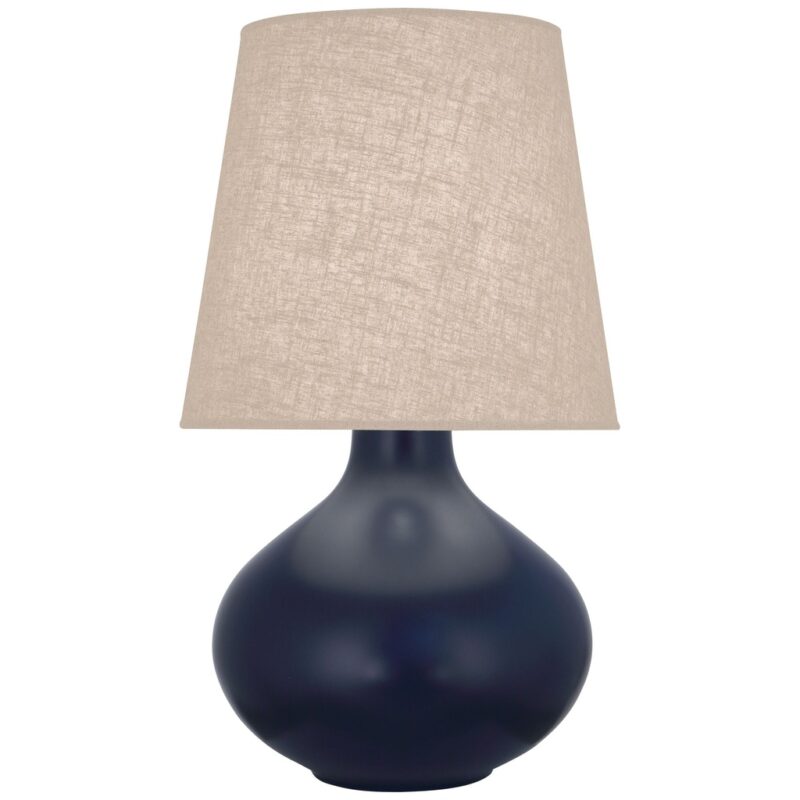Navy blue ceramic table lamps with natural brass hardware on a warm wood nightstand in a jewel-toned bedroom