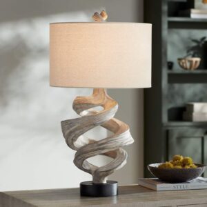 Gold leaf sculptural table lamp on a dark nightstand in a Hollywood Regency bedroom with jewel-toned textiles