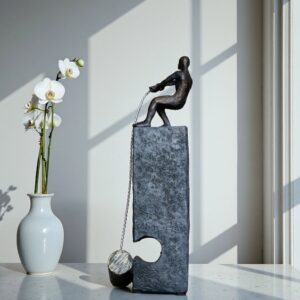 Bronze sculpture for home decor — aged black lamp on a console providing receding lamp presence that lets a dark bronze figurine command the surface