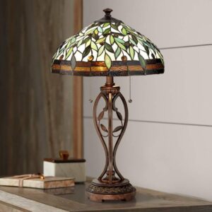 Unusual green tiffany stained glass table lamp shade casting jewel-toned light across a study