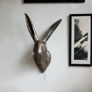 Wood wall sculpture decor for farmhouse interiors — adobe brown chisel lamp on a console beneath a carved wood wall panel in a warm farmhouse living room
