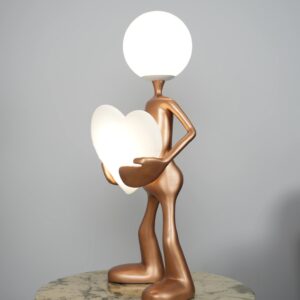 Wall sculpture hanging and lighting — natural beige lamp on a console below a large wall sculpture, angled to create raking uplight across the wall art surface