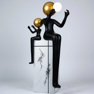 Lighting sculpture at home professionally — natural beige lamp and bronze lamp at opposite ends of a console creating bilateral composition and side lighting for a primary sculpture