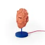 Side view of the terracotta mask lamp showing the red fabric cord