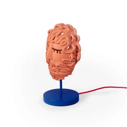 Side view of the terracotta mask lamp showing the red fabric cord