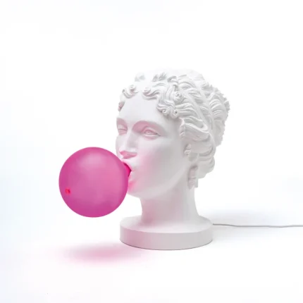 Bubble gum goddess statue lamp glowing on a bookshelf in a neutral living room