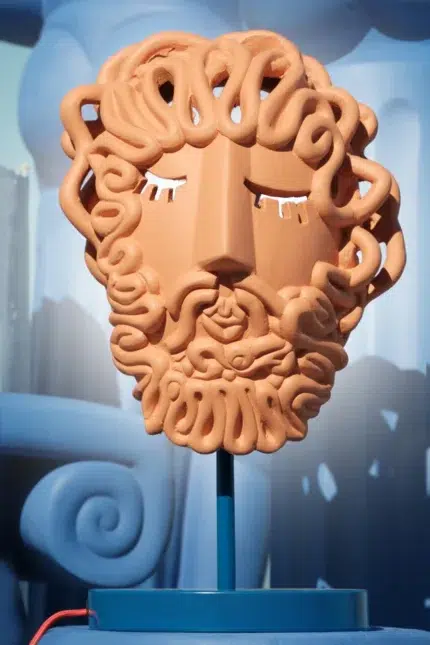 Terracotta lamp — handcrafted Greek mask glowing through pierced eyes on a cobalt-blue base