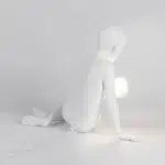 Side view of the sitting boy sculpture lamp showing relaxed pose