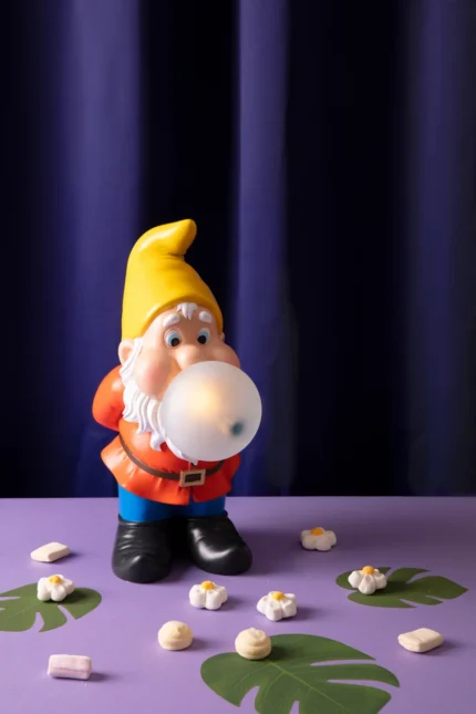 Gnome lamp with yellow cap and red jacket blowing a glowing blue bubble-gum LED bubble