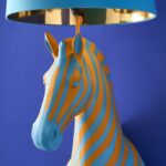 Floor Lamp Zebra Print Blue and Orange, shown illuminated in a living room setting