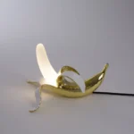 Table Lamp Banana Gold, shown on a sideboard