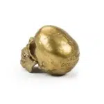 Side view of gold human skull sculpture