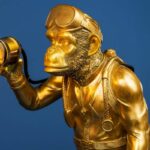 Table Lamp Monkey Diver Gold, shown on a bedside table