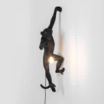 : Wall Lamp Monkey Hanging Black, shown mounted above a fireplace