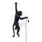 : Wall Lamp Monkey Hanging Black, shown mounted above a fireplace