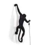 : Wall Lamp Monkey Hanging Black, shown mounted above a fireplace