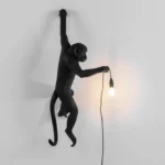 : Wall Lamp Monkey Hanging Black, shown mounted above a fireplace