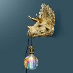 Wall Lamp Triceratops Gold, shown mounted in a living room